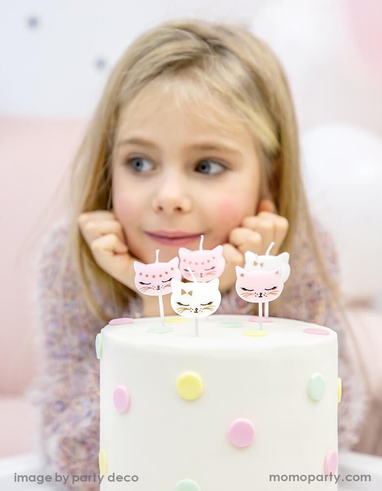 a girl celebration her birthday with a polka dot cake with Kitty Cat Birthday Candles on it