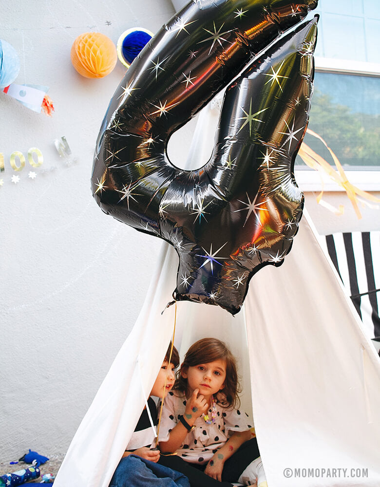 Boy and Girl at Space Themed Birthday Party holding a 38" Black Sparkle Jumbo Number Four Foil Mylar Balloon in the teepee for his 4 years birthday