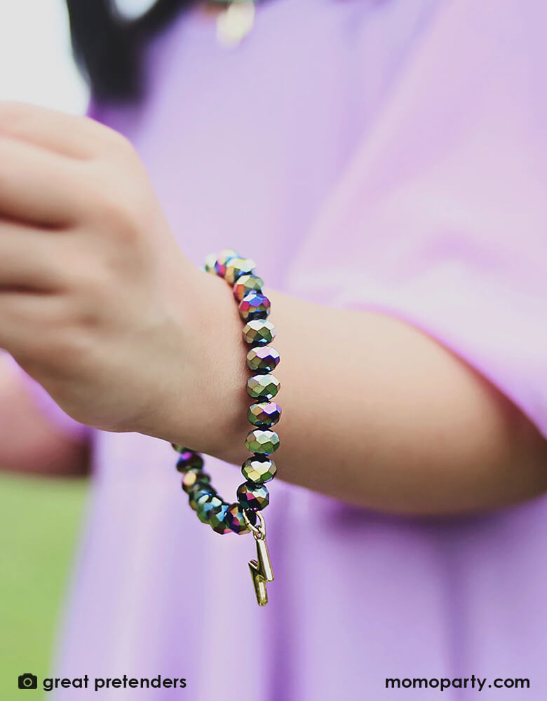 A girl wears the This lightning bolt revolt bracelet holds a dark holographic pattern and a gold lightning bolt charm. 