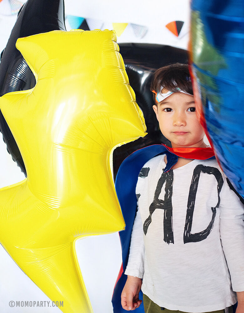 boys standing within Lightning Bolt Foil Balloon, superman emblem balloon, Bat mask Balloons
