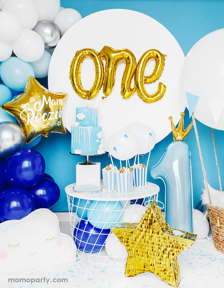 Adorable first birthday party decorated with star fringe pinata, Gold color One Script Foil Balloon, a 2 tire blue cake, sweets in the blue stripe popcorn boxes, lots of blue, white and silver latex balloons garlands, and a 35 inch Little Crown Number 1 Pastel blue Foil Balloon by Party Deco on the side. This adorable party set up is prefect for your baby first birthday party, baby boy 1st year's photoshoot, 1st year celebrations! It's a great way mark your little prince' big milestone!