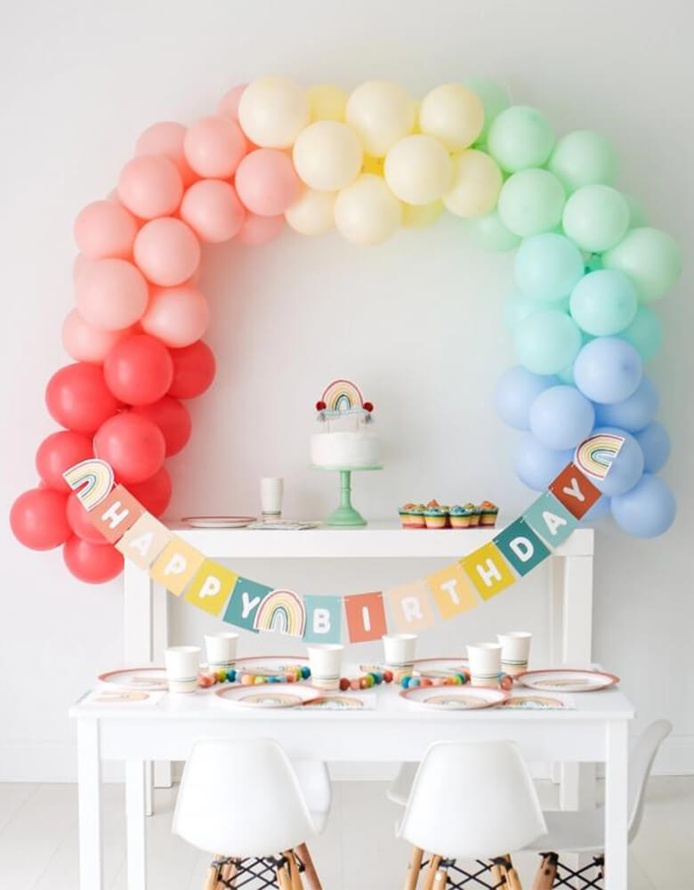 Lucy Darling Little-Rainbow-Party-in-a-Box on a party table_with a Rainbow-balloon garland as the backdrop
