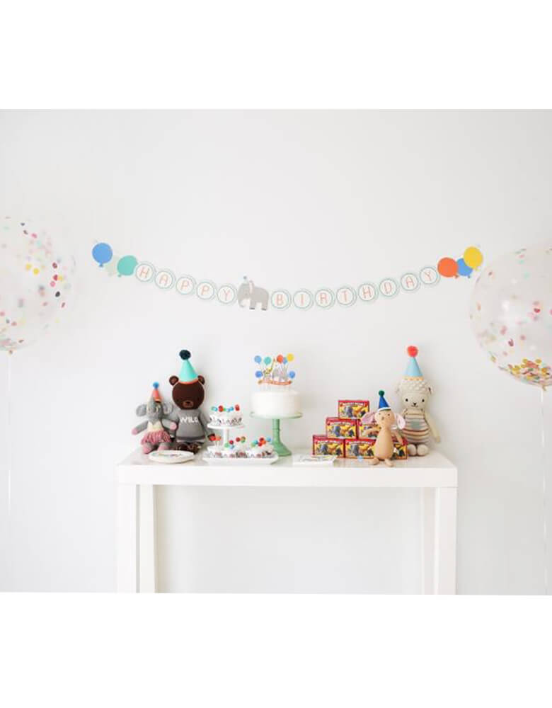 An adorable birthday party table set up with Lucy Darling's party animal birthday banner on the wall and stuffed animals & part balloons as decorations  