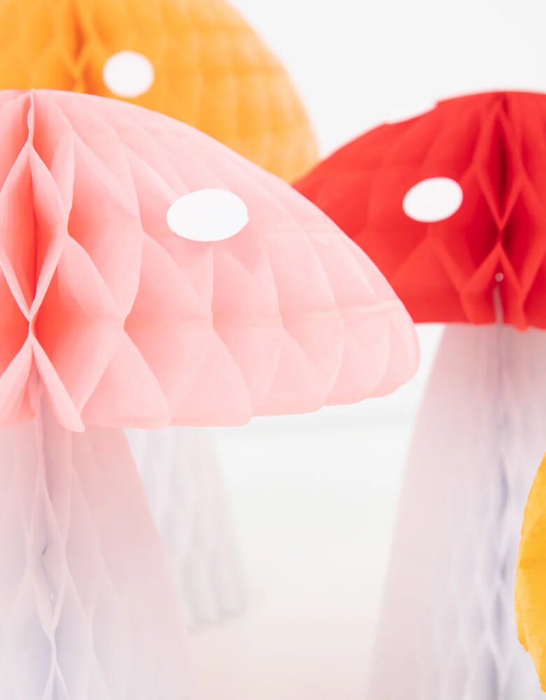 A close up of Meri Meri Honeycomb Mushroom Decorations in the color of orange, pink and red, with white dot accents detail