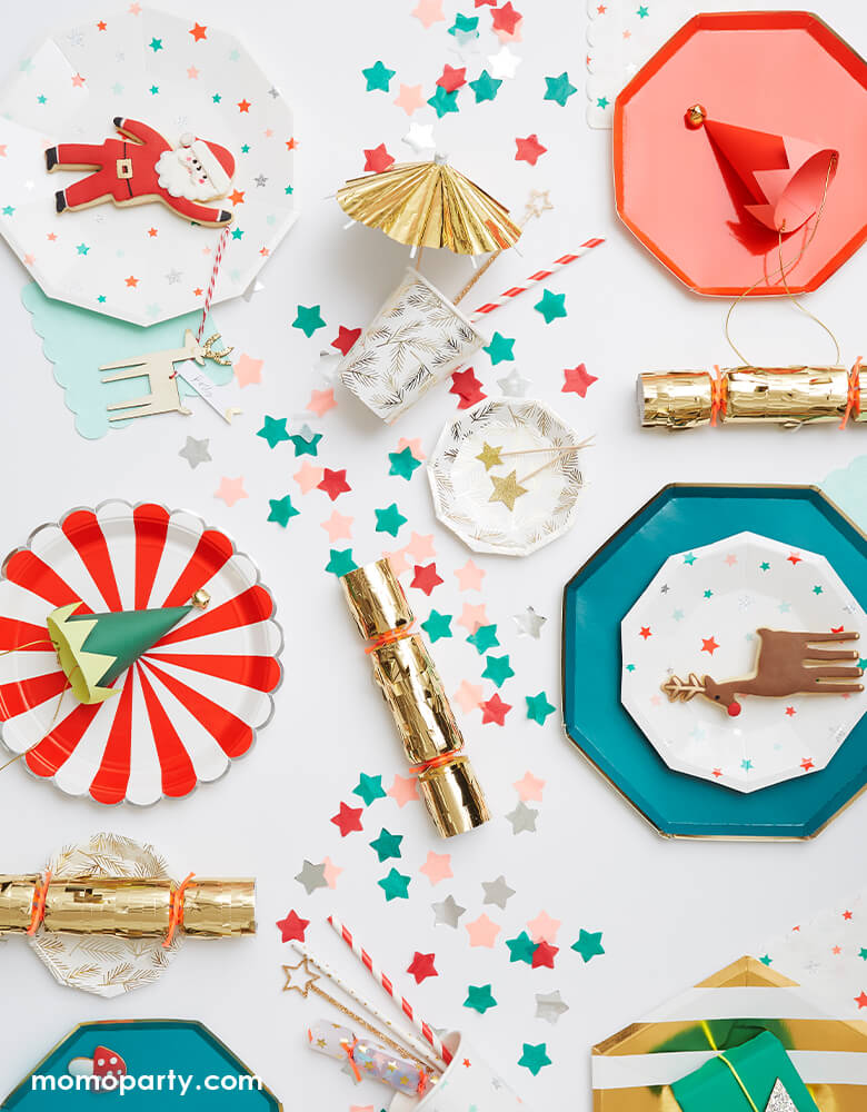 Meri Meri christmas dinner table with full of fun plates. There are Mini Elf Party Hat on top of Red Side Plate and Red Fan Stripe Large Plates,, Reindeer cookie on top of Stars plates and Dark Teal Dinner Plate, star shaped confetti as centerpiece for a fun christmas party