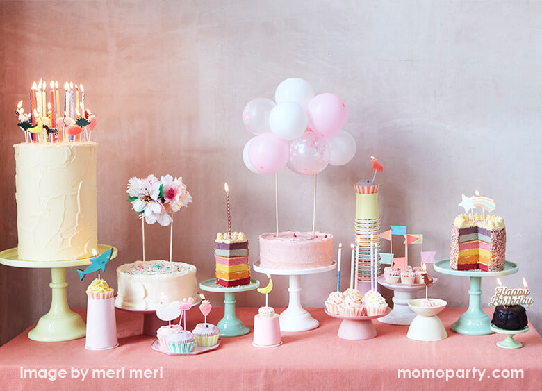 Long table with many cakes and cupcakes on the colorful cake toppers, decorated with candles, cake toppers, cupcake toppers designed by MeriMeri party