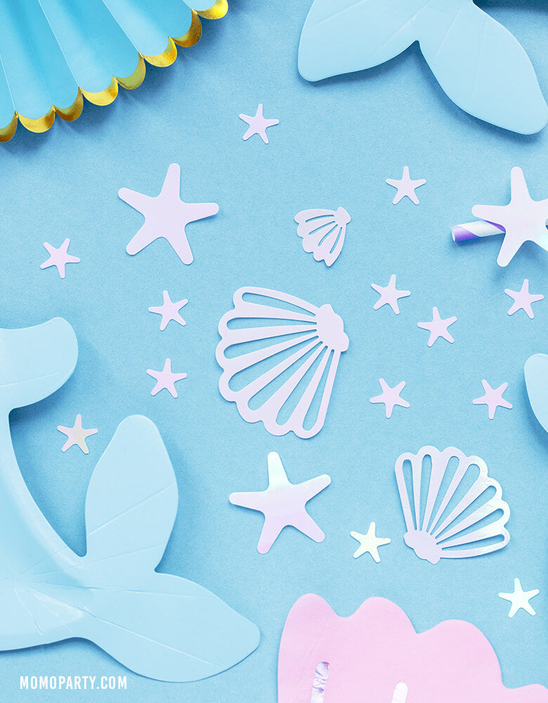 Close up of Party Deco Mermaid Narwhal Iridescent Confetti over a pale blue tabletop