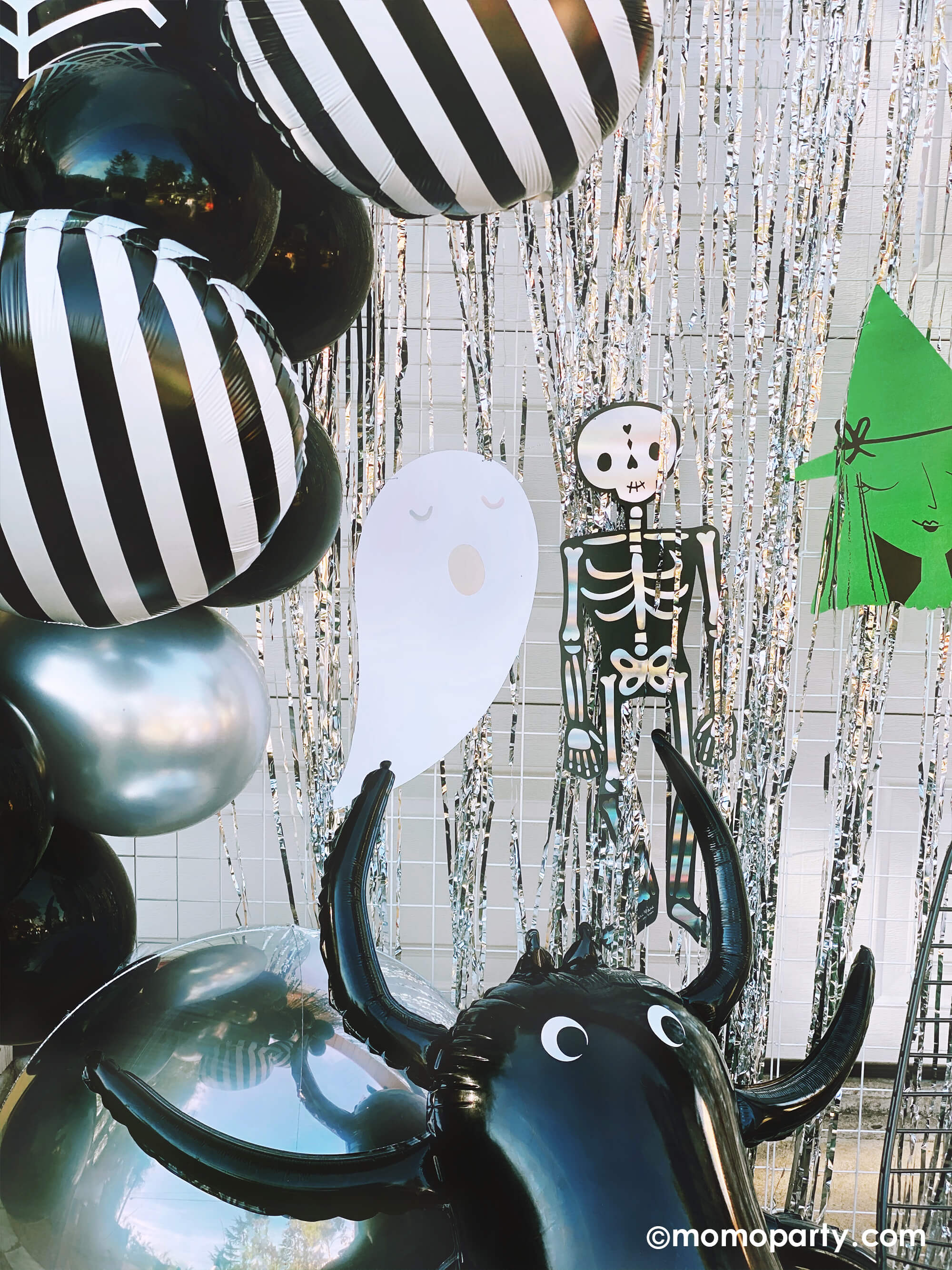 close up of Momo party Halloween birthday party, decorated with Junior Vertical Stripes Black and White Foil Mylar Balloon, Giant Spider Foil Balloon,  Halloween Motif Large Garland in the front of silver curtain. 