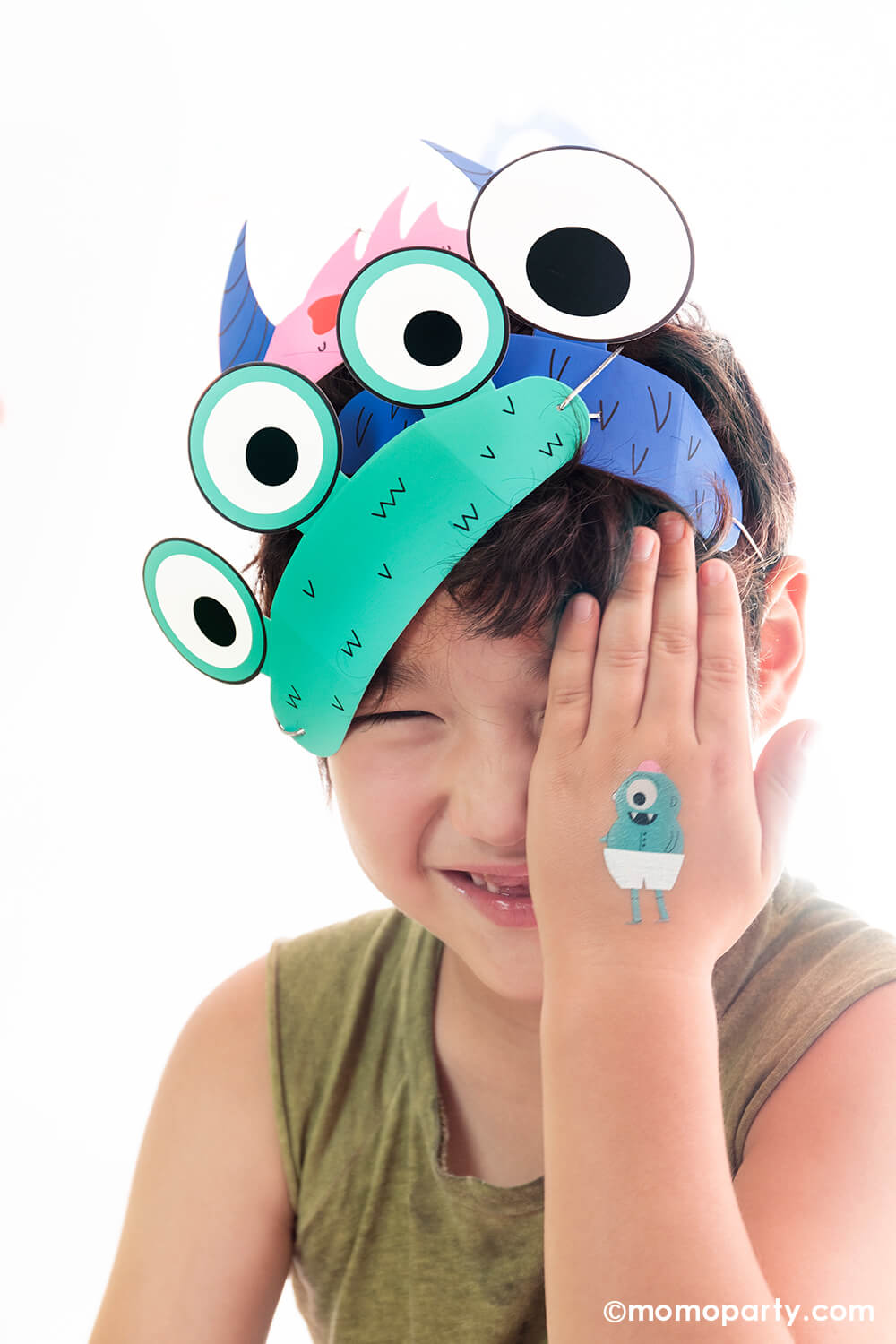 A boy playing peek a boo cover his eye with one hand with a cute Little Monsters Temporary Tattoo on it, he is wearing Little Monsters Party Headband Set on his head, This Super modern cute Jollity & Co Party Boutique - Daydream society collection is perfect for Little Monsters themed birthday party, halloween party or monster inc themed birthday party