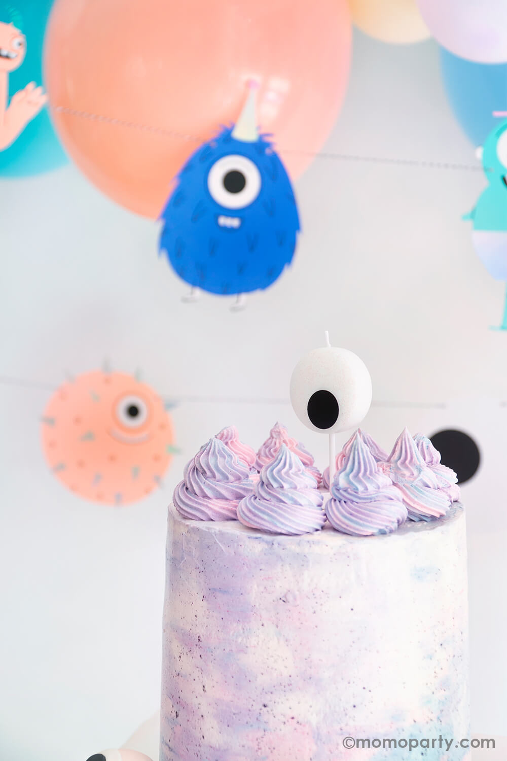 close up look of modern pastel watercolor buttercream cake with Little Monsters Large Eyeball Candle by Jollity & Co Party Boutique - Daydream society collection. With  Little Monsters Garland and pastel color themed balloon as decoration. Super cute collection for Little Monsters themed birthday party, halloween party or monster inc themed birthday party