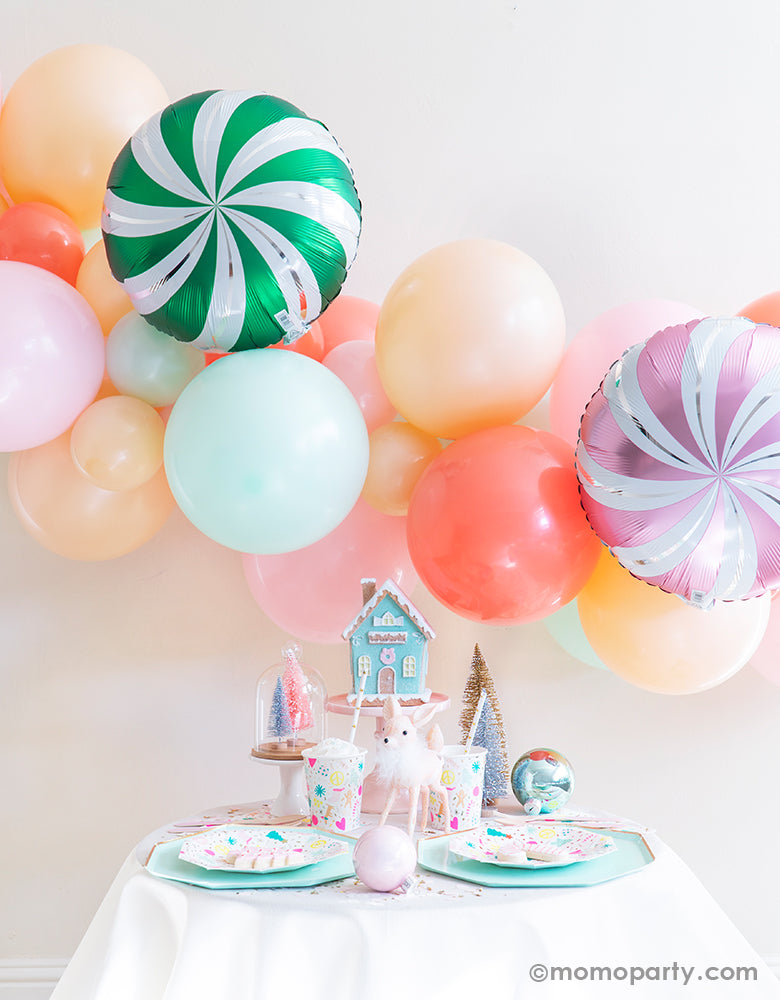 Merry & Bright Christmas Holiday Boxes with Pastel Color themed mint, peach, pink balloon garland and CANDY SWIRLS FOIL MYLAR BALLOON as backdrop, Meri Meri Mint Large Dinner Plates, and Day dream societyMerry and Bright Small Plates, Napkins and Cups as tablewares for a modern cute pastel holiday party idea
