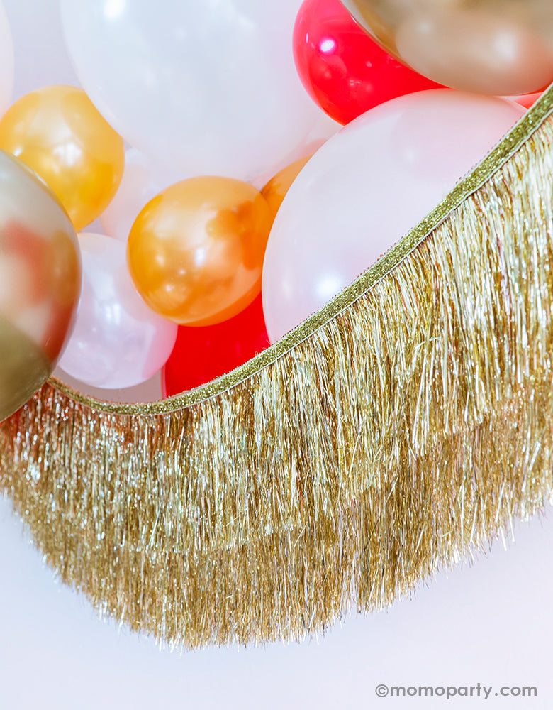 Momo Party Holiday party decoration idea Featuring Gold, Red, Pearl White, Coral, Pearl peach latex balloons with Meri Meri gold tinsel fringe garland