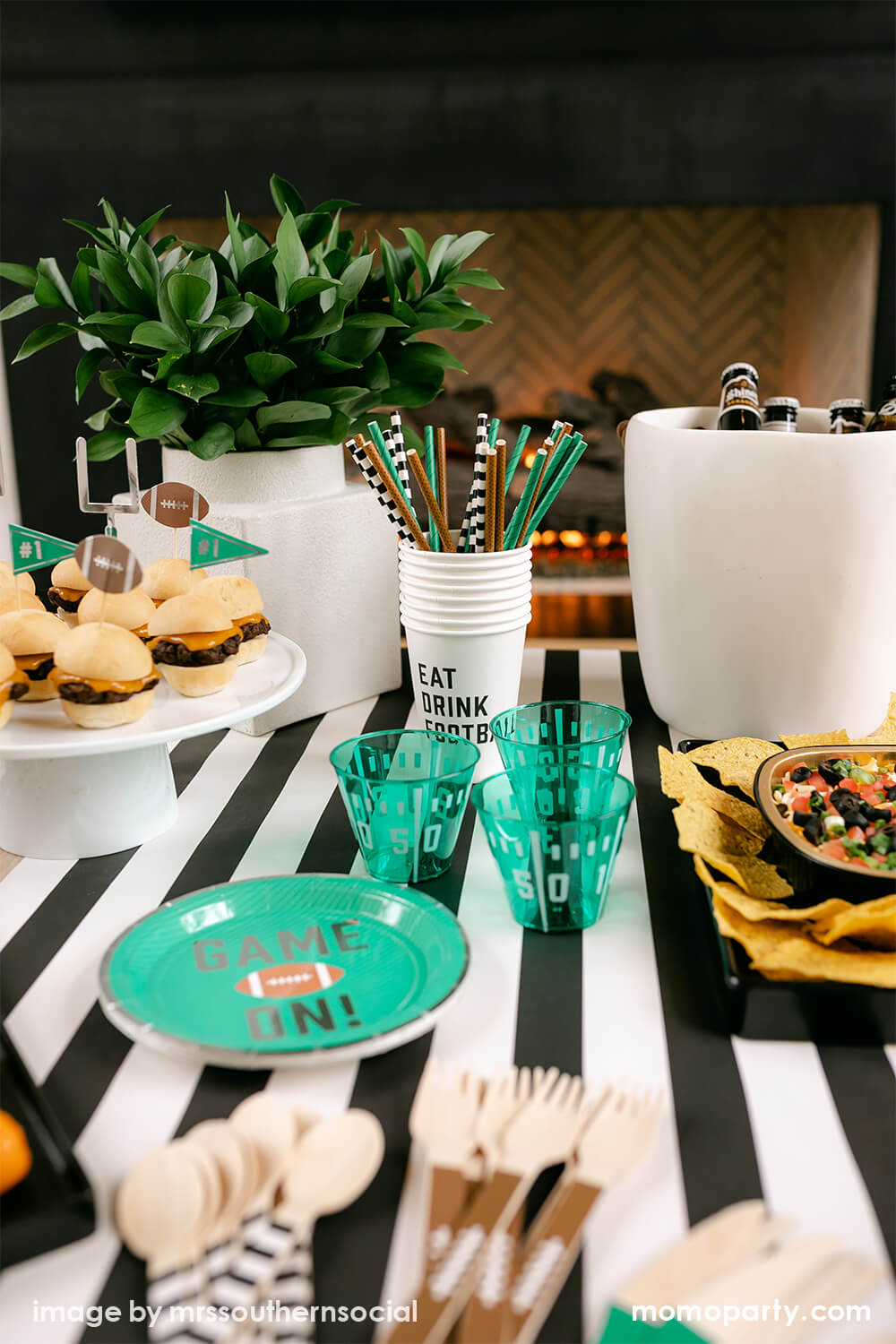 Football Party inspo, close up table look with cakewalk true brands Green Game on Football Party Paper Plates, Yard Line Plastic Cups, Football Tailgate Party Straws inside of Eat Drink Football Paper Cups, chips on the black container on the side, with on top of the Hester & Cook simple striped runner. These modern table styling are perfect for super bowl party and entertaining with family and kids
