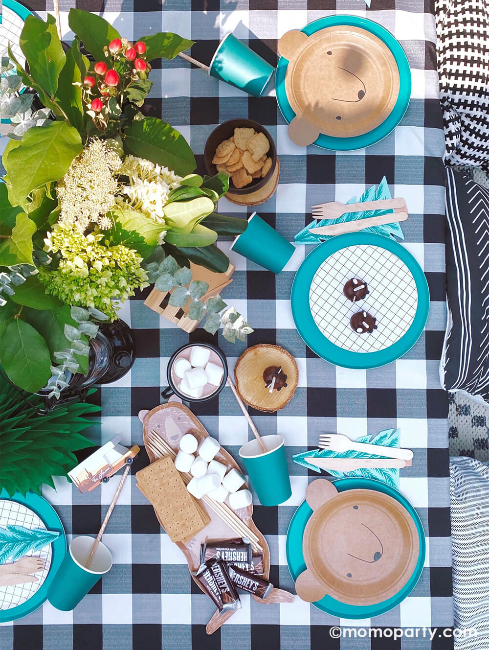 Kid's Woodland Camping outdoor birthday party, kid table decorated with Bear small plates and black and white small plates layered with Oh happy day forest green 9 inch Plates, Meri Meri tree napkins with wooden utensils, black campfire mugs, brown bear platter with Hershey's milk chocolate bar, marshmallows and graham cracker ready for smore, fresh flowers, green Tree tissue decor, all over the black and white Checkered Gingham tablecloth for a modern camping themed birthday party