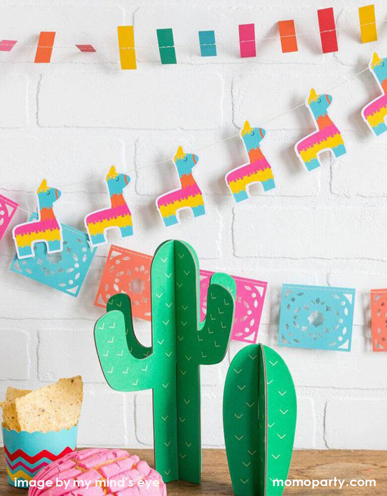 Fiesta celebration dessert table decorated with My-Minds-Eye Fiesta Cactus Tabletop Decor as centerpiece, Chips in the Fiesta Food Cups, My-Minds-Eye Mini-Banner-Set with ticker tape banner, llama banner, and papel picados banner as backdrop. These modern and Easy set up party ware are perfect for your next Taco Tuesday gathering, Fiesta birthday party, boho fiesta baby shower, cinco de mayo celebration