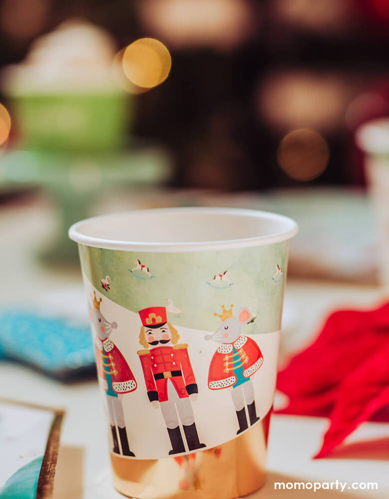 Cozy Holiday party table close up details of a Nutcracker Holiday Party cups, printed with whimsical classic Nutcracker characters of Nutcracker, Mouse King designs. for a warm cozy holiday dinner. these high quality eco friendly party cups  will set a scene worthy of a standing ovation for your home or a nutcracker lover christmas party