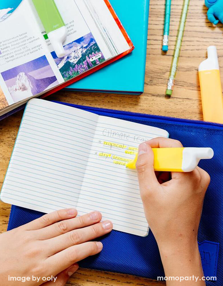 ooly Do-Overs Erasable Highlighters in use in a notebook with book and pencils around