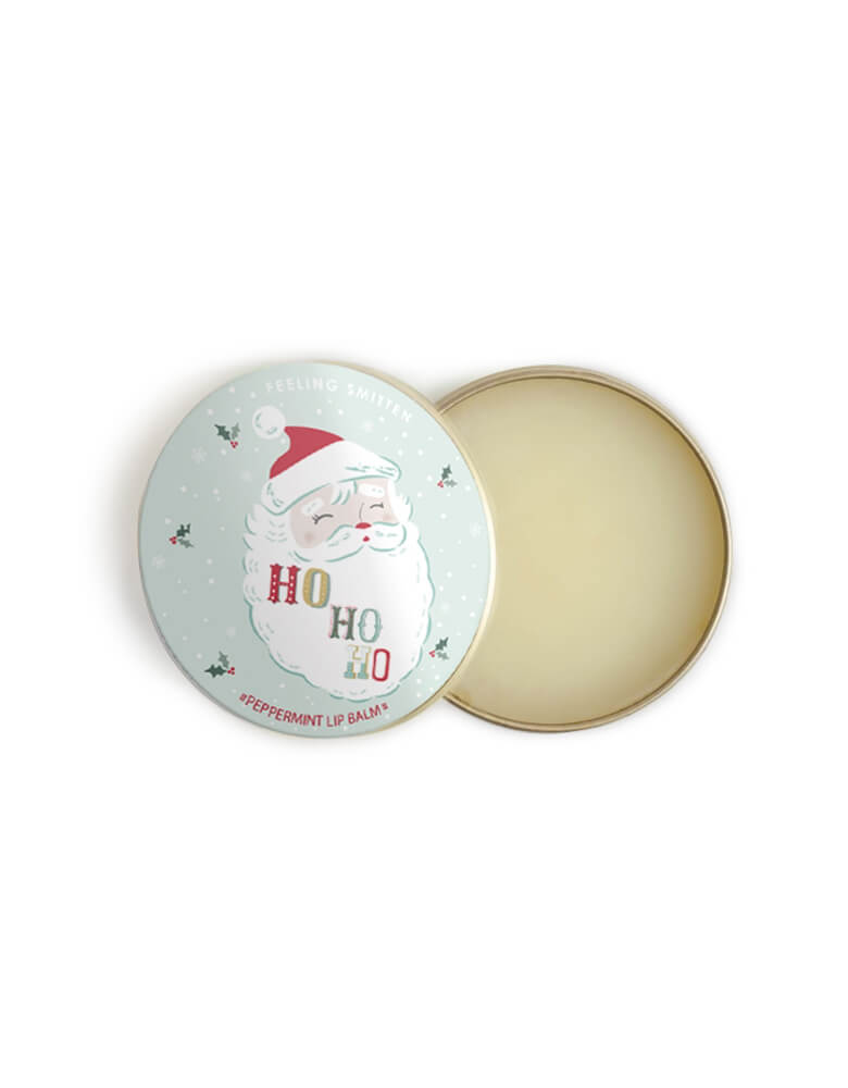 Feeling Smitten - Peppermint Santa Lip Balm. Featuring featuring beeswax and shea butter in a small rounded tin with Santa graphic and HOHOHO text on it. The weather outside may be frightful but your lips will feel delightful with this vanilla-kissed lip balm, naturally hydrate and protect against dry skin. use yourself or kid, sent it as gift to your loved one, it also a perfect for stocking stuffers 