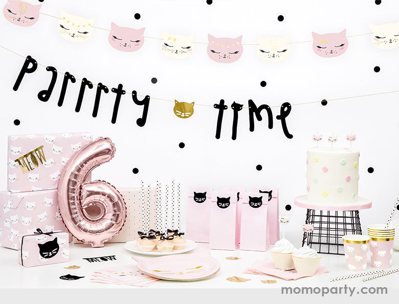 A kitty cat themed birthday party look, decorated with Party Deco Kitty cat garland, Parrrrty time garland, a Rose gold number 6 foil balloon in front of party gifts warp with pink cat wrapping paper, cake decorated with polka dots and kitty cat candles, party deco cat plates, napkins and cups in front of the table, pink party paper bags with black cat sticker, cake pops. These cat themed party supplies are super cute for a girls birthday, cat lover's birthday, pet themed party