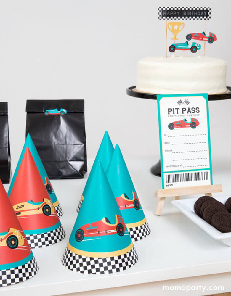 Race car birthday party, dessert table decorated with a white cream cake with race car cake toppers, a PIT PASS card,cookies, Race car party hats, gift bags  