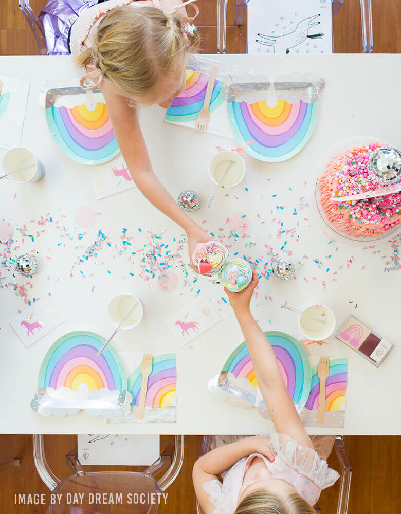Girls celebrate a rainbow party with Day Dream Society over the rainbow die cut large paper plates and napkins, lots of rainbow color confetti