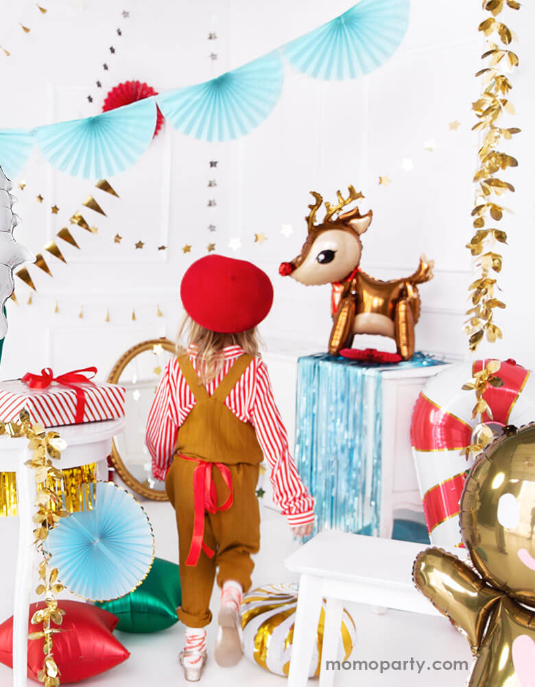 A little girl walking into A Christmas party set up filled with festive Christmas foil balloons including reindeer balloons, candy cane balloons and gingerbread man balloons
