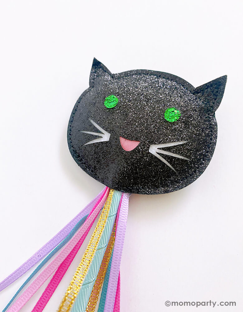 Close up details of rockahula kids - Lucky Black Cat Wand. Featuring a black shining glitter black cat with green sequins eyes, a happy face with beautiful colored ribbons, this is the perfect handmade high quality wand for imagination adventures or a fun addition to your little one's Halloween dressing up box!