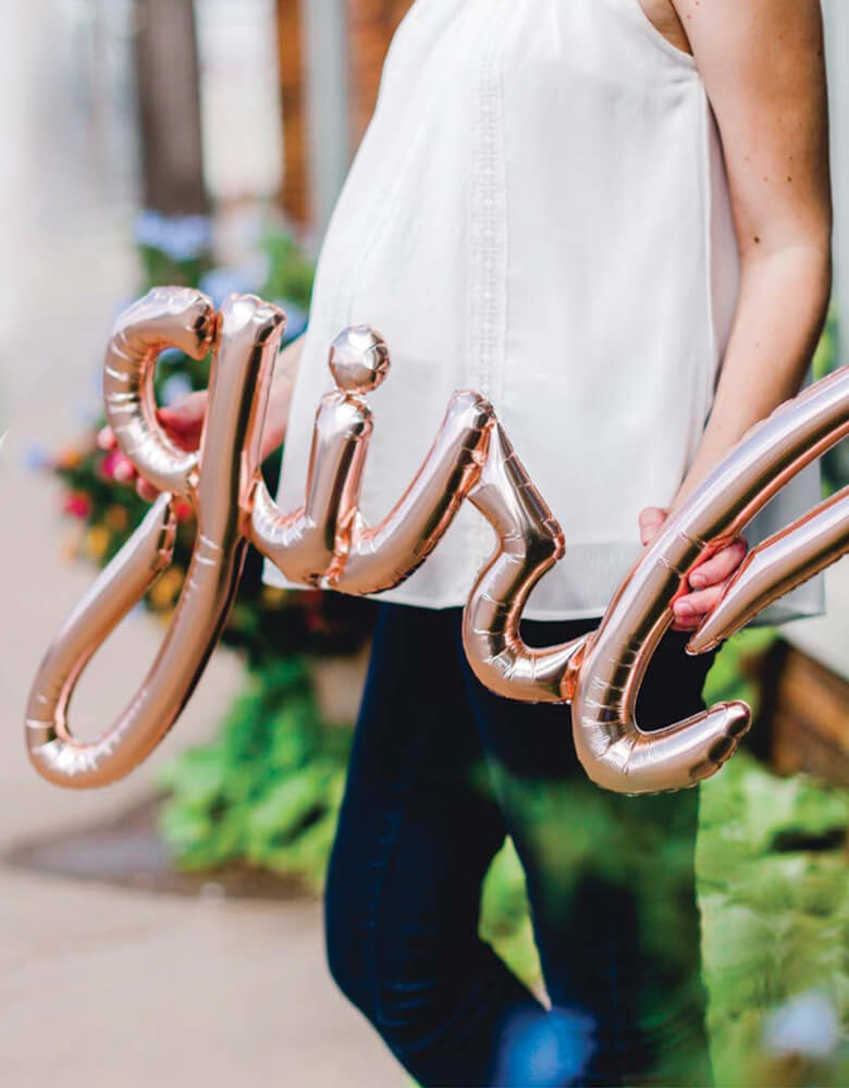baby shower Mom to be holding a Rose-Gold-Girl-Script-Foil-Balloon