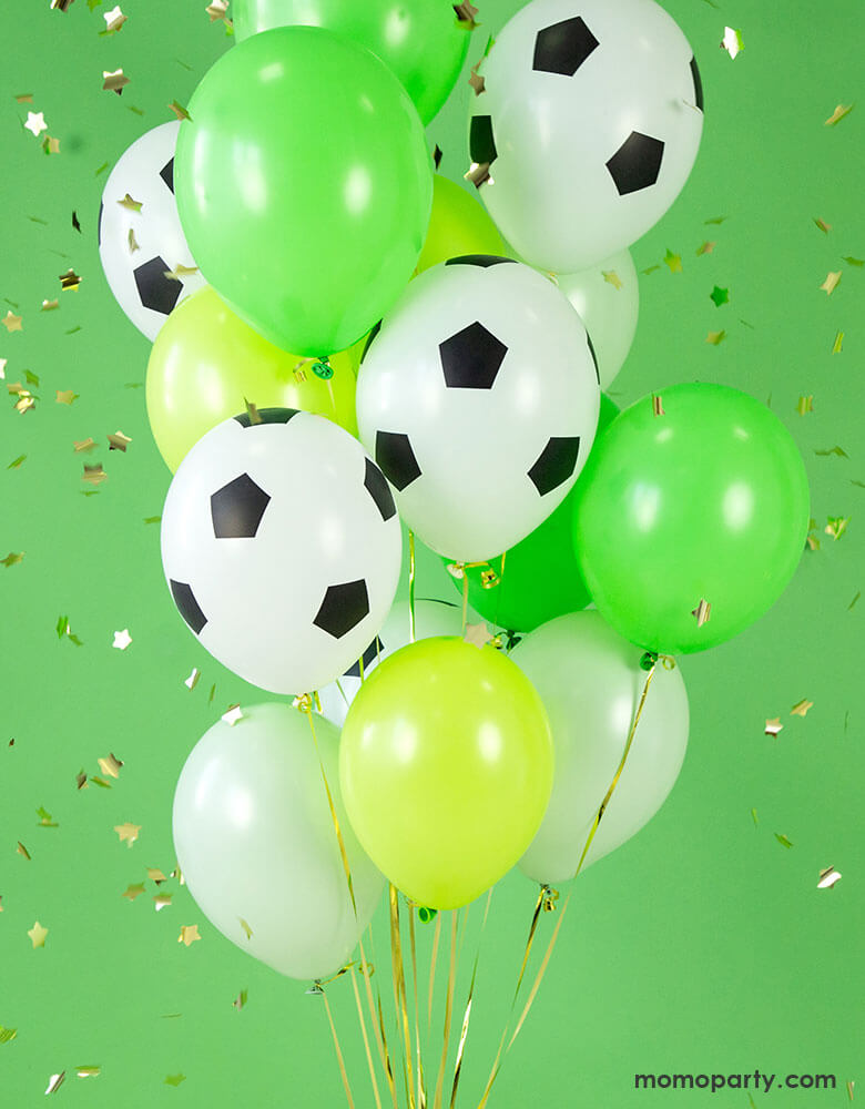 A balloon bouquet with party deco's 11" soccer balloon and a mixture of solid latex balloons in bright green, lime green, and ivory with gold confetti in the background perfect for a soccer themed party