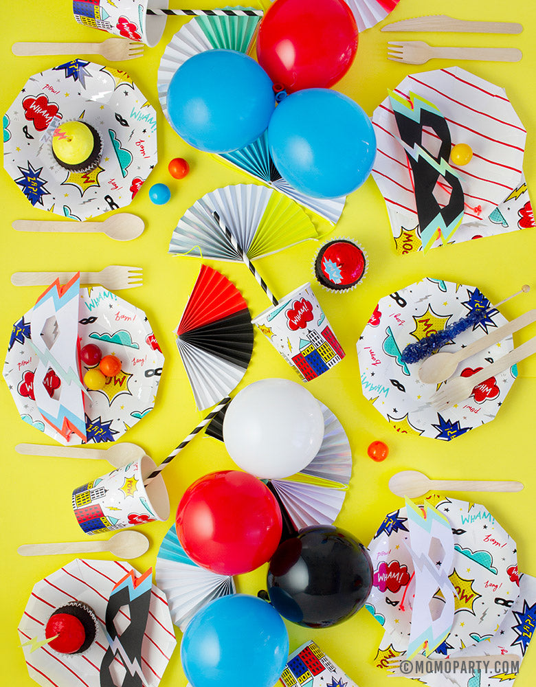 Kids superhero themed birthday party table set up with daydream society superhero plates and cups, colorful balloons as centerpiece 