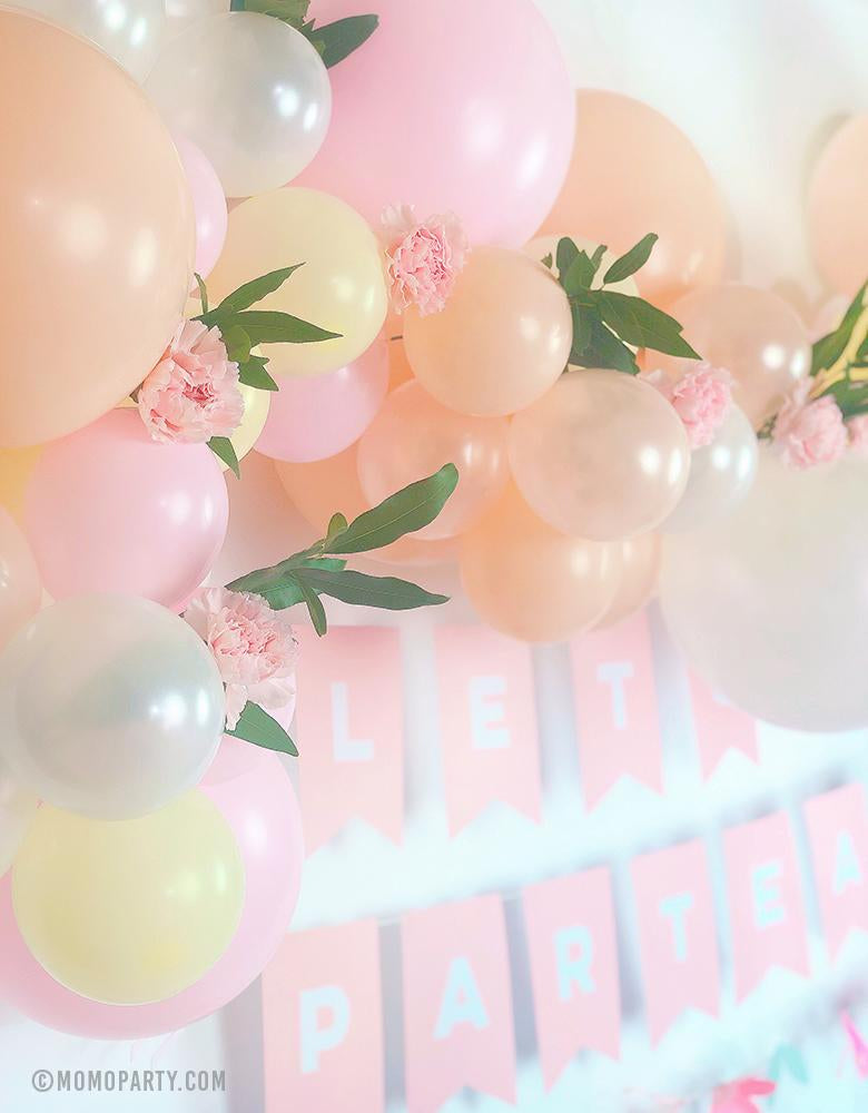 A beautiful pink blush pastel balloon garland with flower decoration and Pink letter banner of "Lets Partea" for a floral pastel tea party birthday celebration 