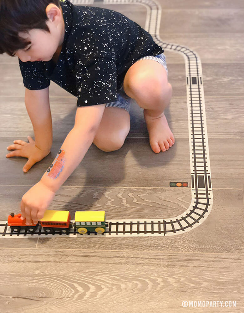 Boy playing train wooden toys on Train Track Tape on the floor