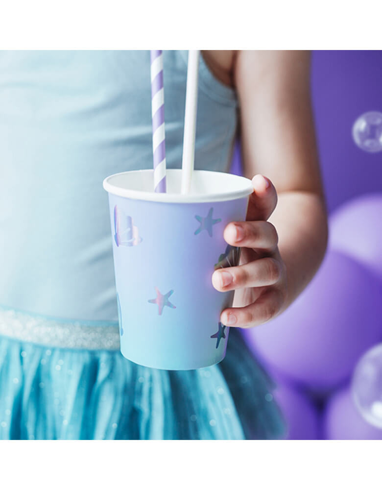 Kid's holding a Party Deco Under The Sea Cup in front of a lilac mermaid backdrop