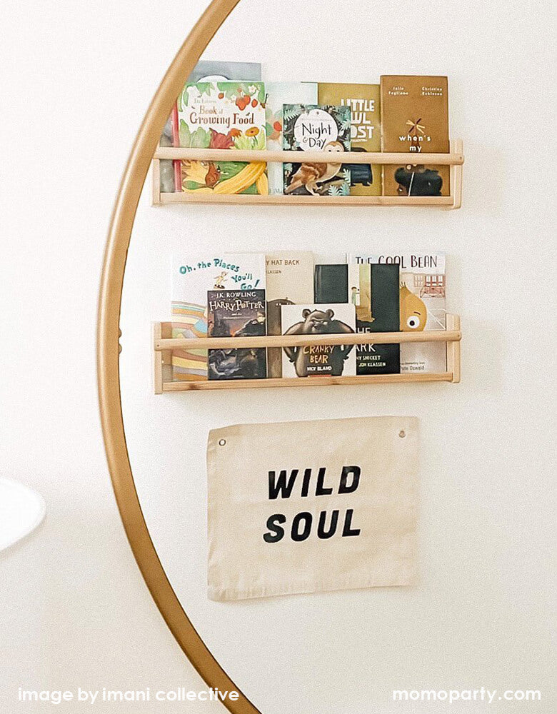 Imani Collective Wild Soul Banner. Nature canvas with black screen print text of Wild Soul, hanging under a kids wooden book shelf