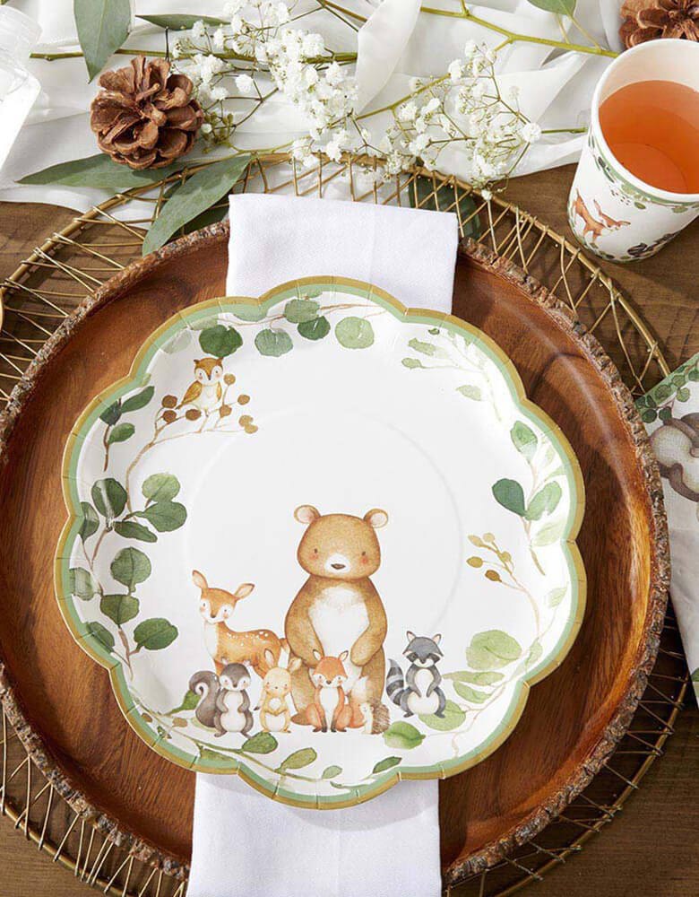 Woodland Baby Large Paper Plate by Kate Aspen. These premium disposable plates have a gold foil border followed by a border of greenery with an arrangement of woodland animals at the base.