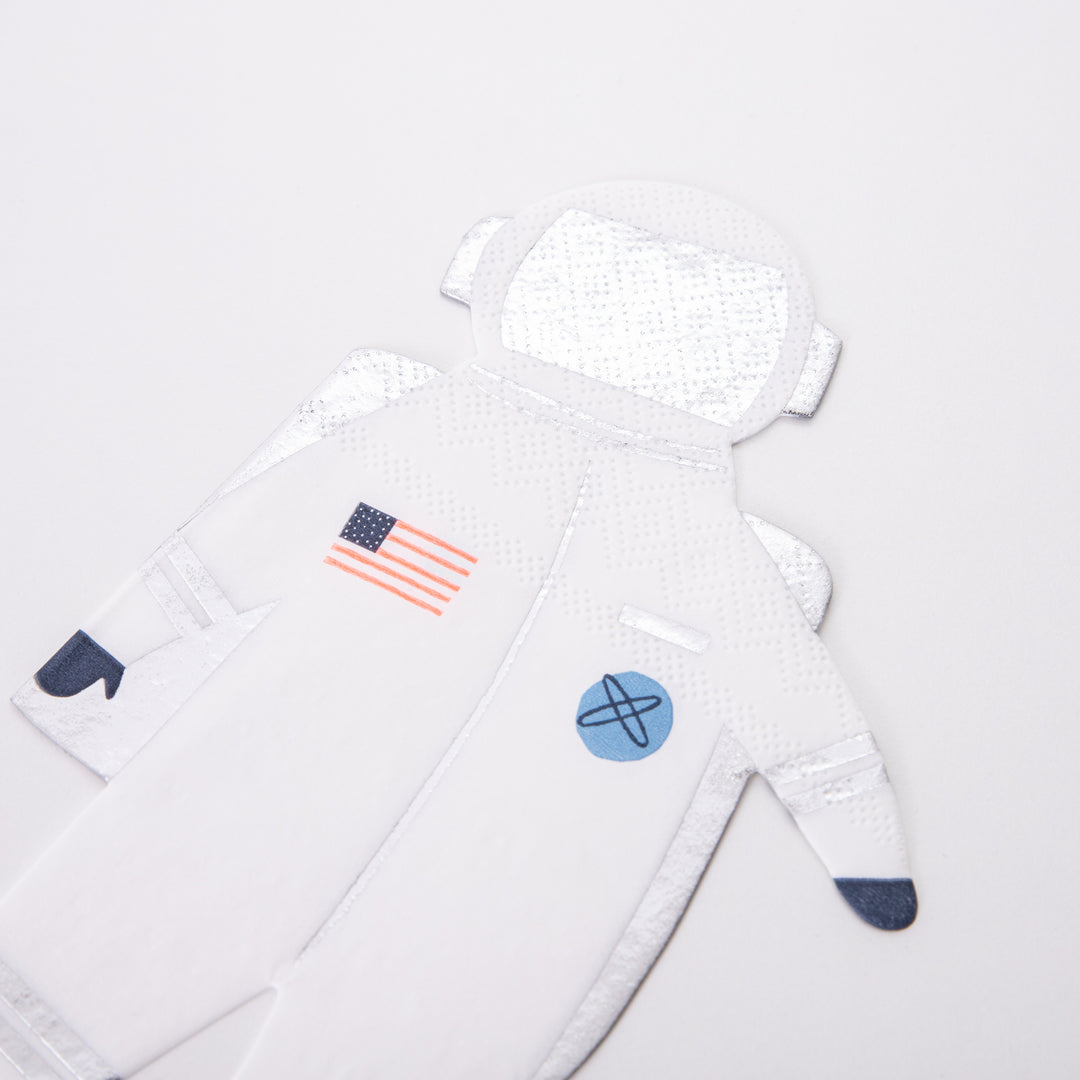 A close up of Meri Meri's Astronaut die cut napkin, crafted from 3-ply paper with silver foil detail,  perfect for a space themed birthday, blast off birthday, two the moon birthday party or all type of space themed event and celebration