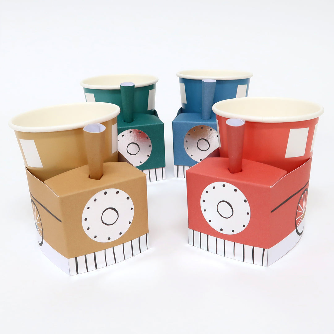 Momo Party 3D Train cups by Meri Meri.  Pack of 8 in 4 colors of blue, red, yellow and green, at size 9 oz. capacity, they're perfect for kid's birthday party. Simple self assembly required. Cups are made of 3 easy-to-assemble pieces - cup, cup wrap and funnel