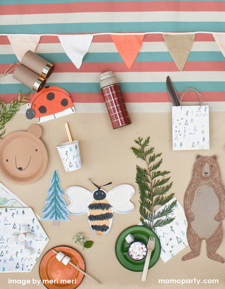 Woodland Camping party tabletop filled with Meri Meri Bear Small Plates, Ladybug Napkins, Meri Meri Bee Plates, Brown Bear plate, Let's Explore Large Plates napkin and cups, Let's Explore party bag with a feature inside, s'mores, a small cup of hot chocolate with marshmallow, color stripe tablecloth and a kid telescope, enjoy the fun with this modern look and fun designed woodland camping party for your summer holiday
